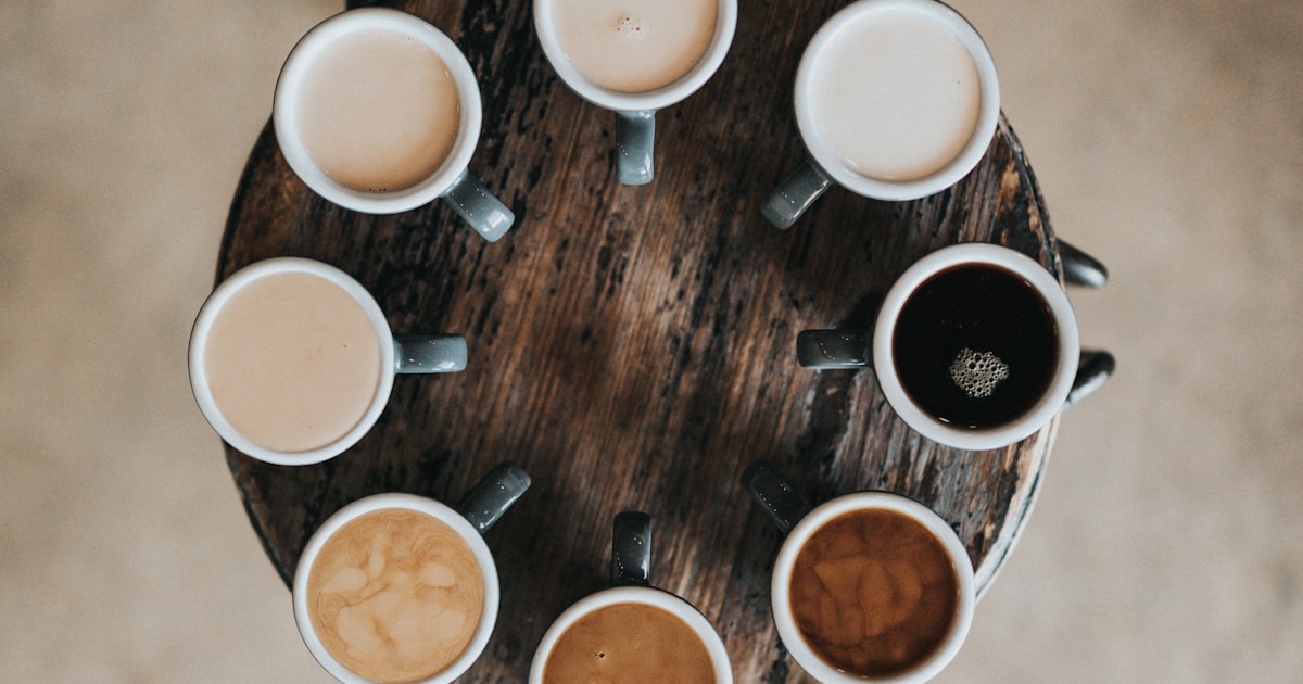 Collection of ceramic and stainless steel coffee mugs on a wooden table