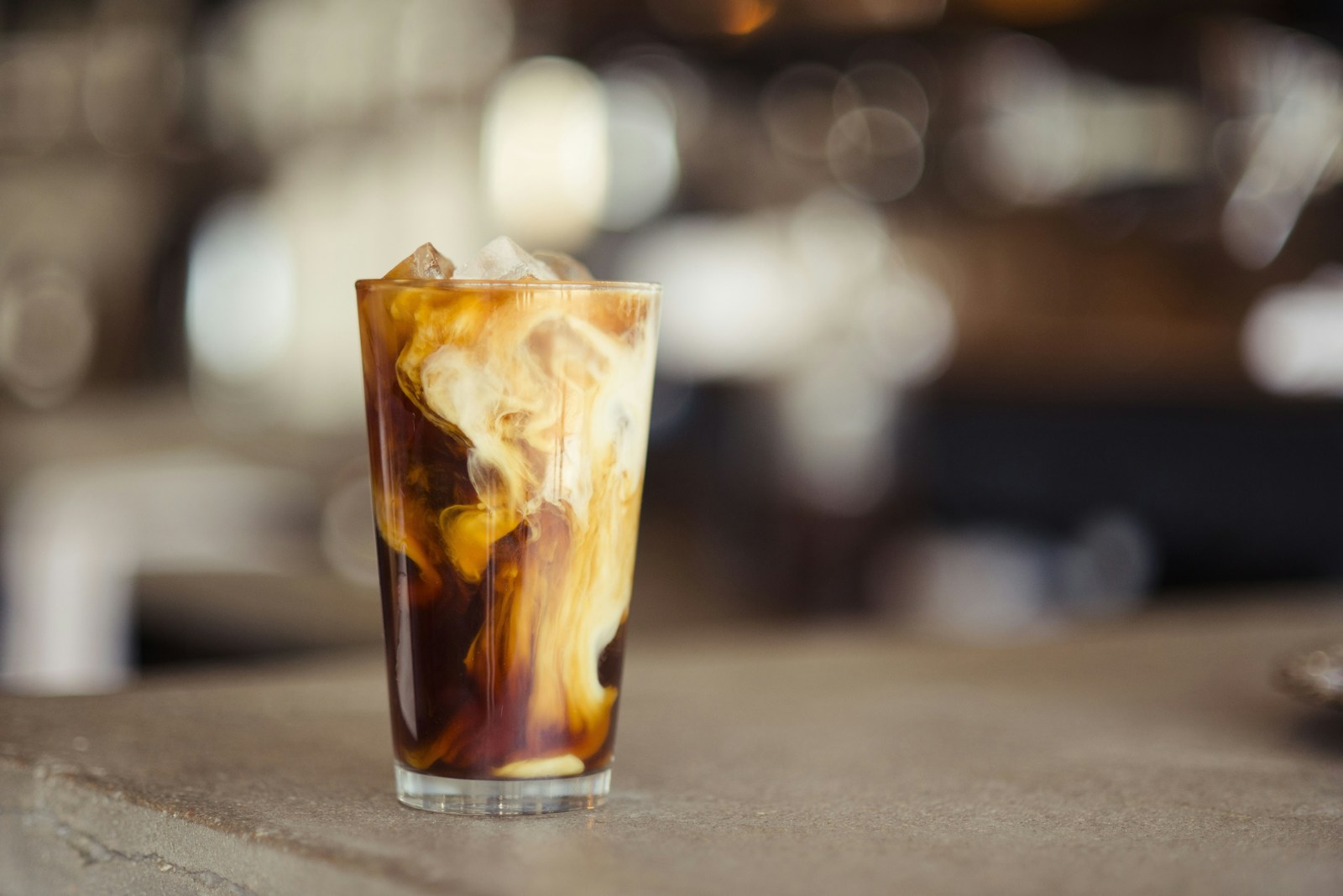 Iced coffee in a tall glass with ice cubes and a straw