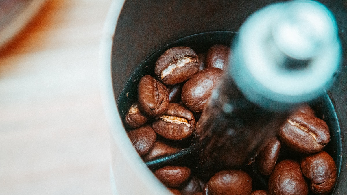 Coffee grinder filled with coffee beans on a wooden surface