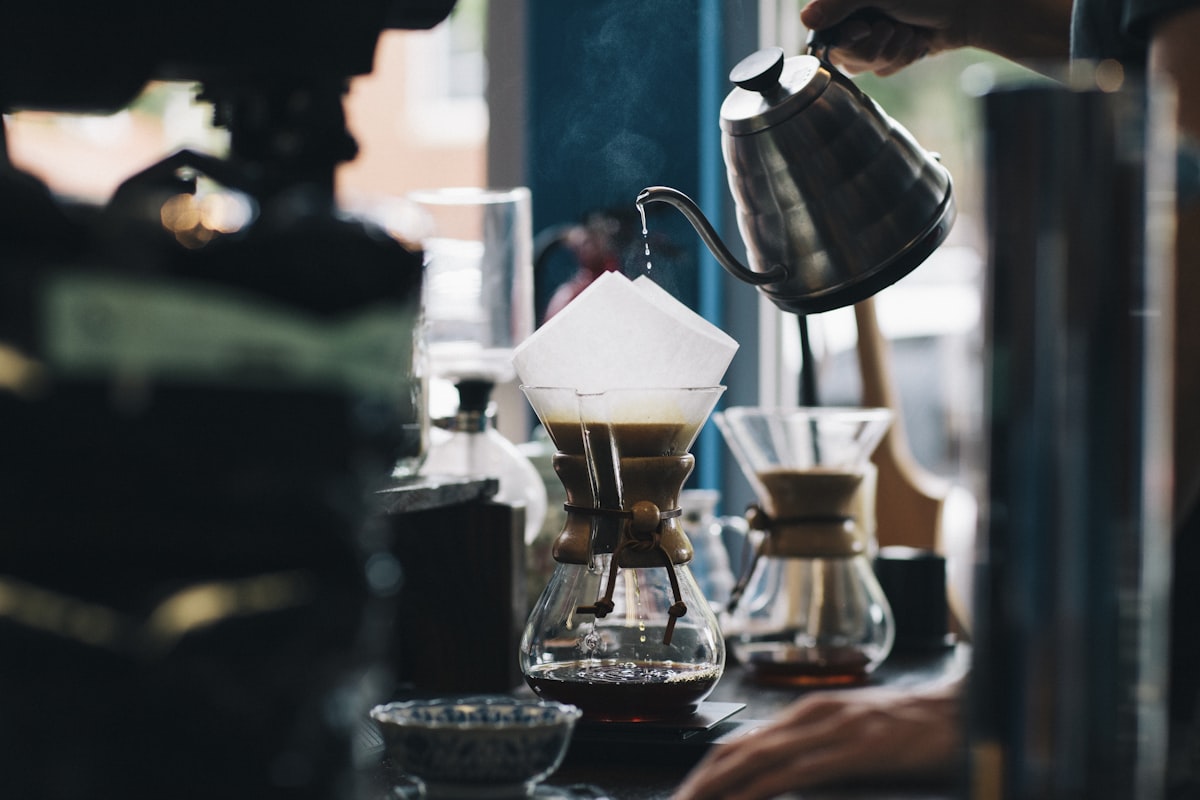 Pouring hot water from a gooseneck kettle over coffee grounds in a filter