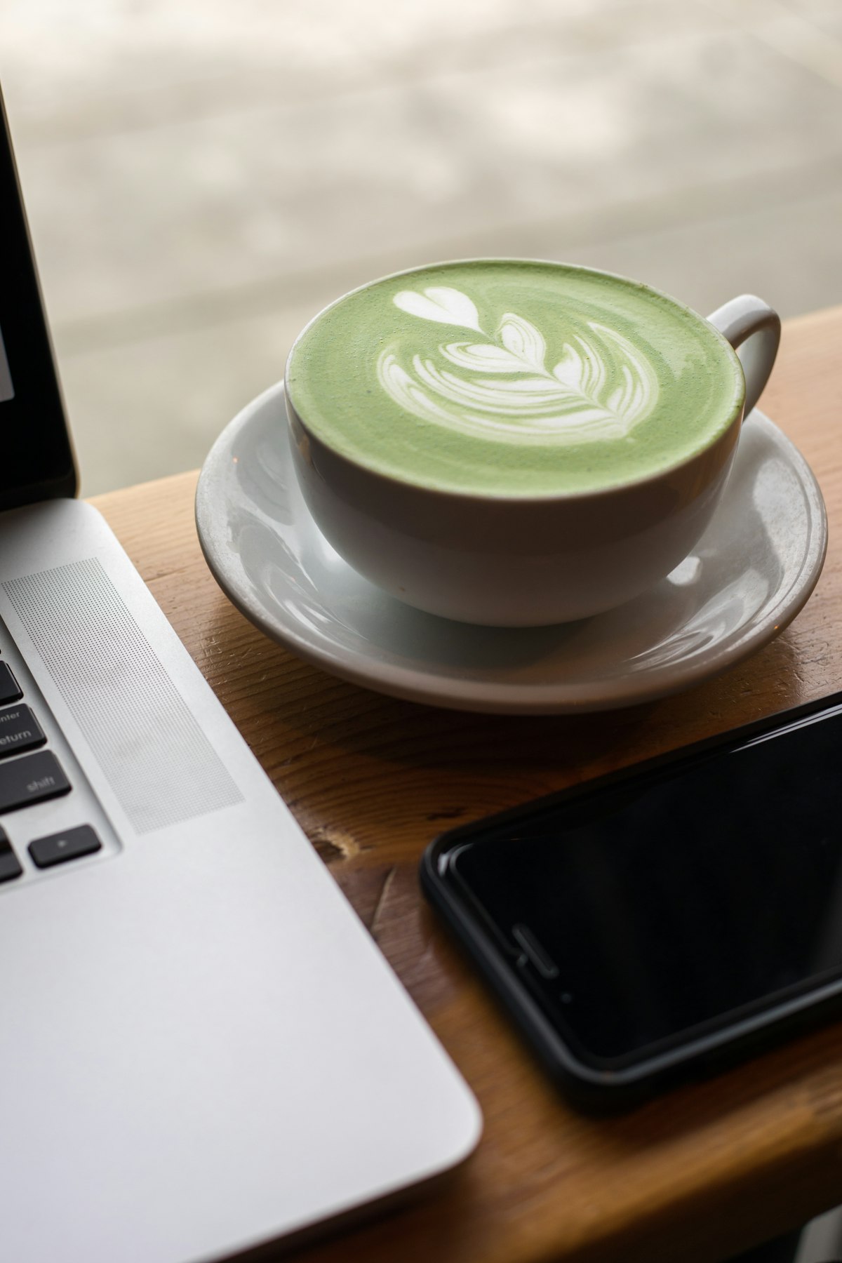 A takeaway latte in a paper cup beside a home espresso setup, comparing the cost of coffee shop coffee with brewing at home