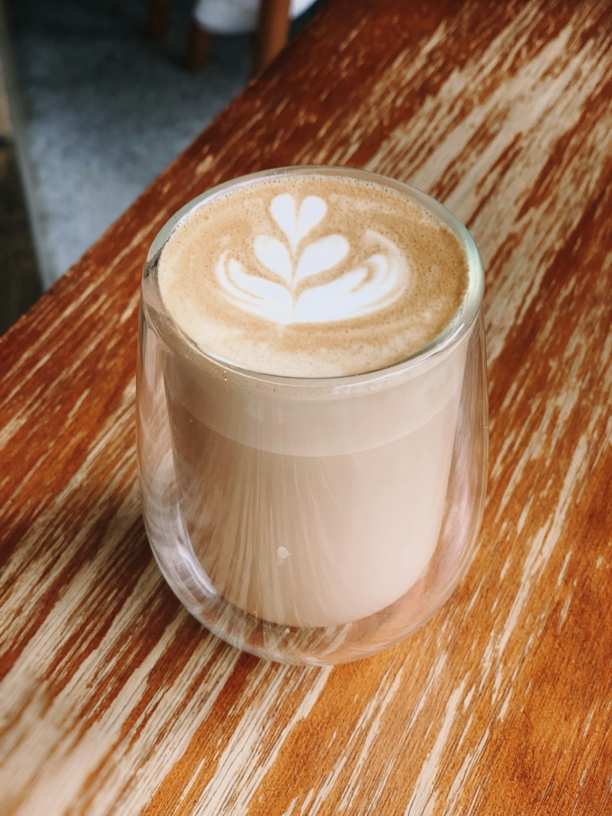 Homemade coffee syrup in a glass bottle next to a cup of flavoured latte