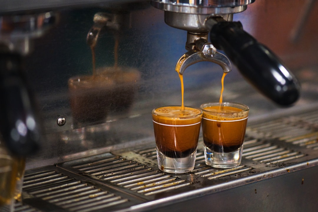 Espresso shot being pulled into a glass cup from a coffee machine